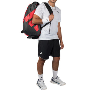 Man draagt de zwart-rode Adidas Racket Bag Multigame 2026 als rugzak op zijn rug.