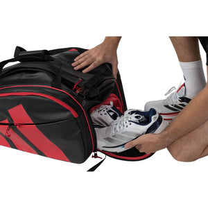 Sportschoenen worden in het zijvak van de zwart-rode Adidas Multigame 2026 gestopt.