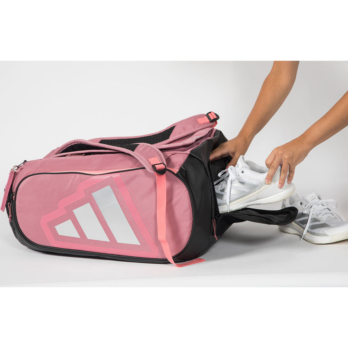 Witte schoenen worden in het zwarte zijvak van de roze Adidas Protour 2026 geschoven.