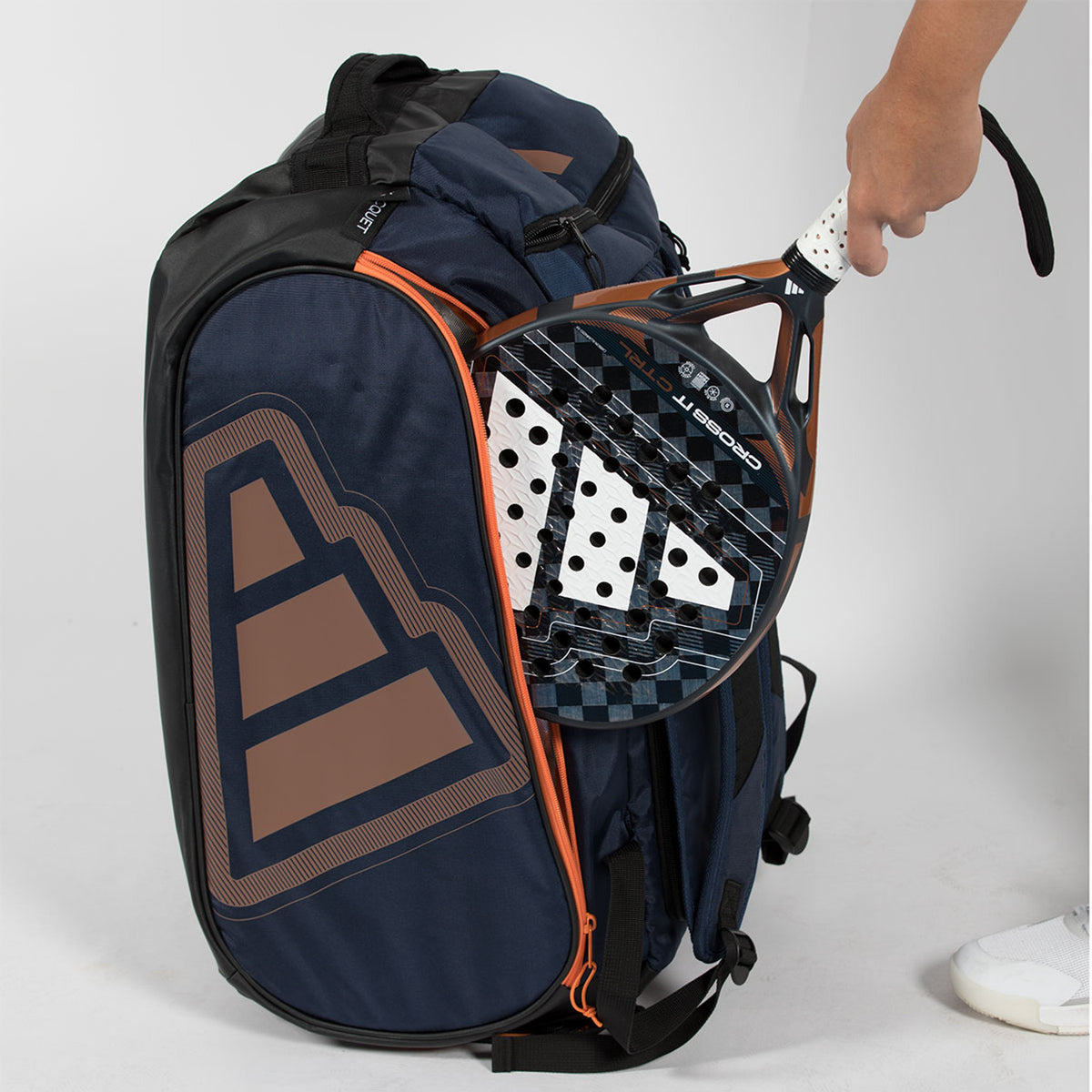 Hand haalt een racket uit het vak van de marineblauwe Adidas Protour 2026 racketbag.