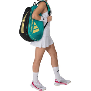 Speelster draagt de groene Adidas Control 3.4 racketbag op haar rug in witte outfit.