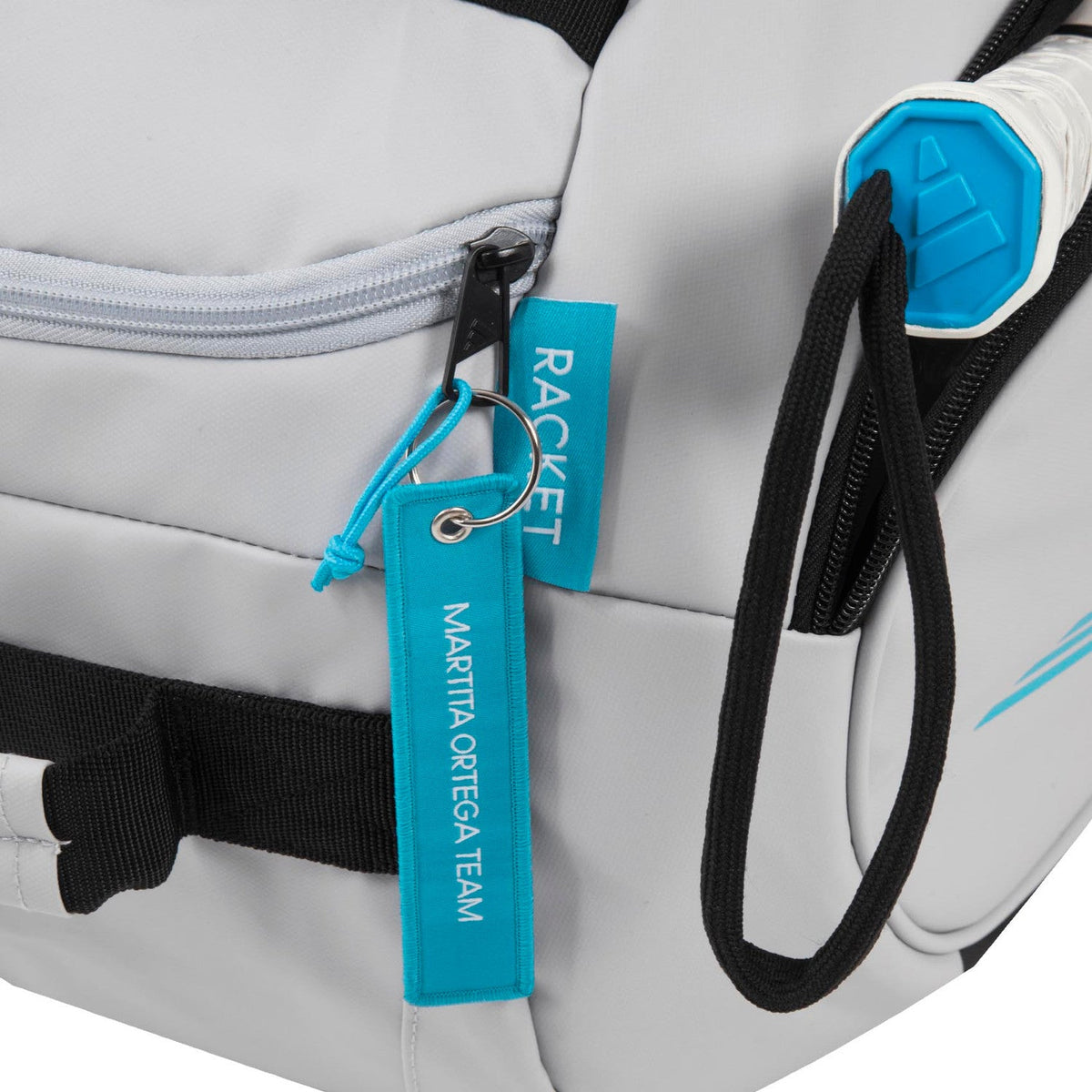 Detail van het turquoise hanglabel op de witte Adidas Protour 3.4 racketbag.