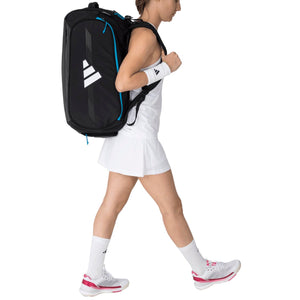 Speelster draagt de zwarte Adidas Protour 3.4 racketbag op haar rug in witte rok.