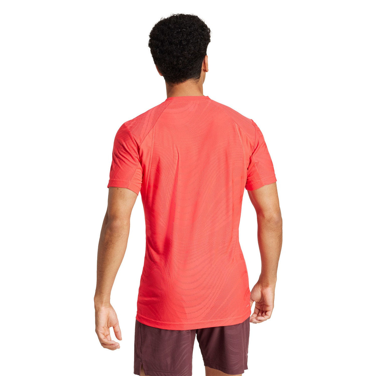 Achteraanzicht van model in het koraalrode Adidas Freelift Pro T-shirt met korte mouwen