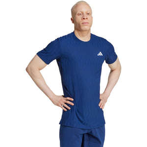 Model draagt het kobaltblauwe Adidas Freelift T-shirt met handen in de zij