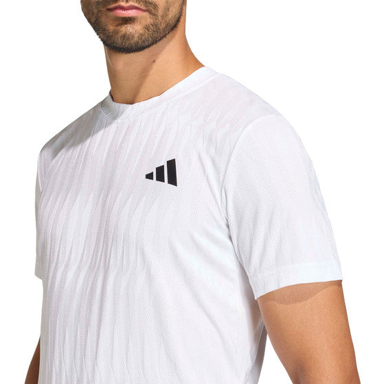 Close-up van het zwarte borstlogo op het witte Adidas Freelift T-shirt