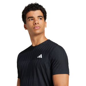 Model draagt het zwarte Adidas Freelift T-shirt, close-up van het borstlogo