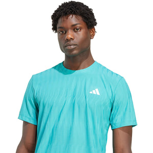 Close-up van het witte borstlogo op het turquoise Adidas Freelift T-shirt