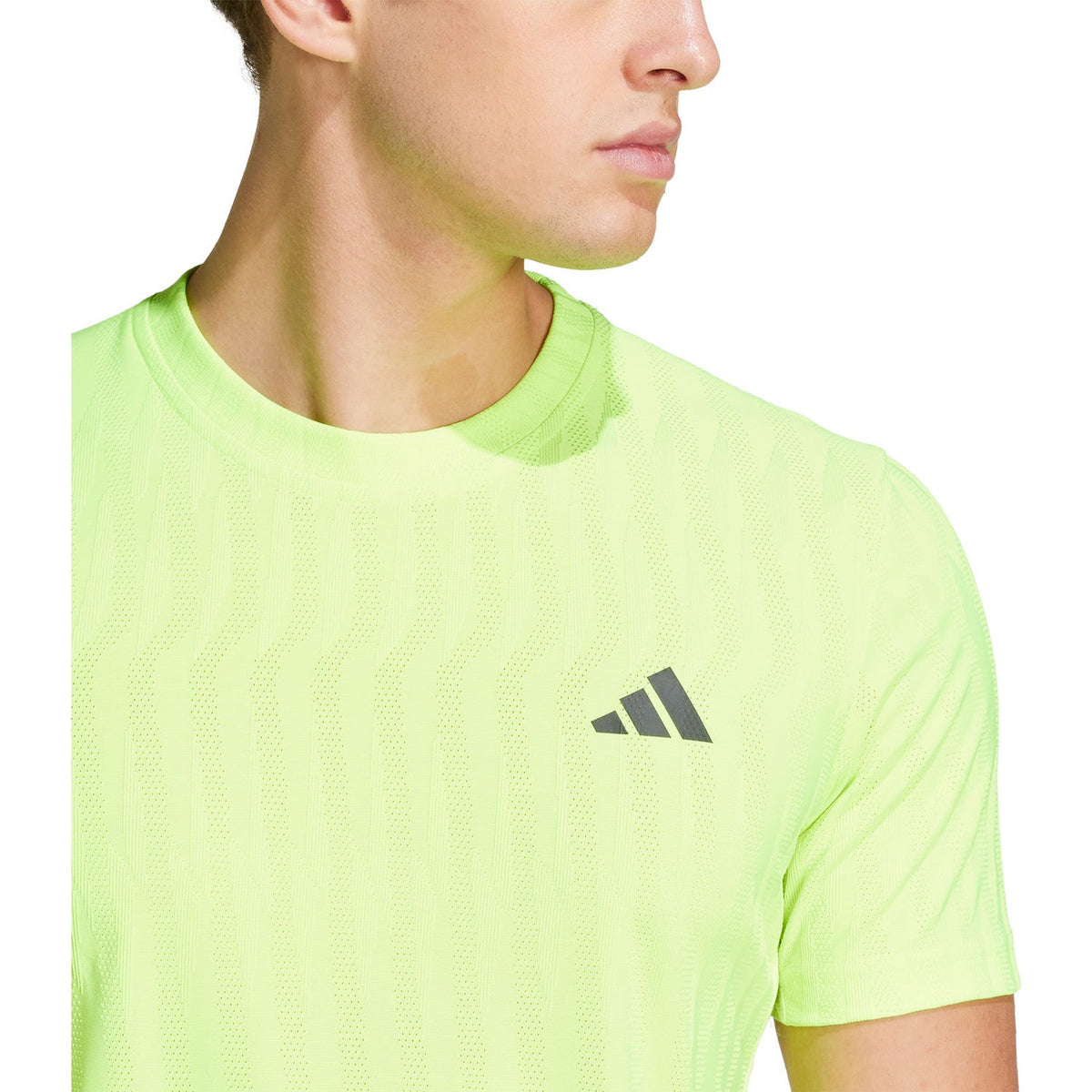 Close-up van het logo op het limoengroene Adidas Freelift T-shirt