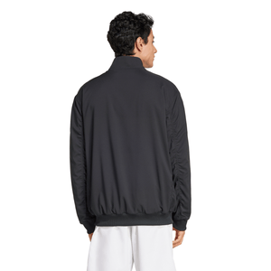 Achteraanzicht van model in het zwarte Adidas Walk On jack met witte broek