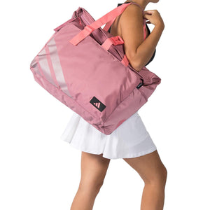 Model draagt de roze Adidas Weekend Bag 2026 aan de schouderbanden in witte rok.