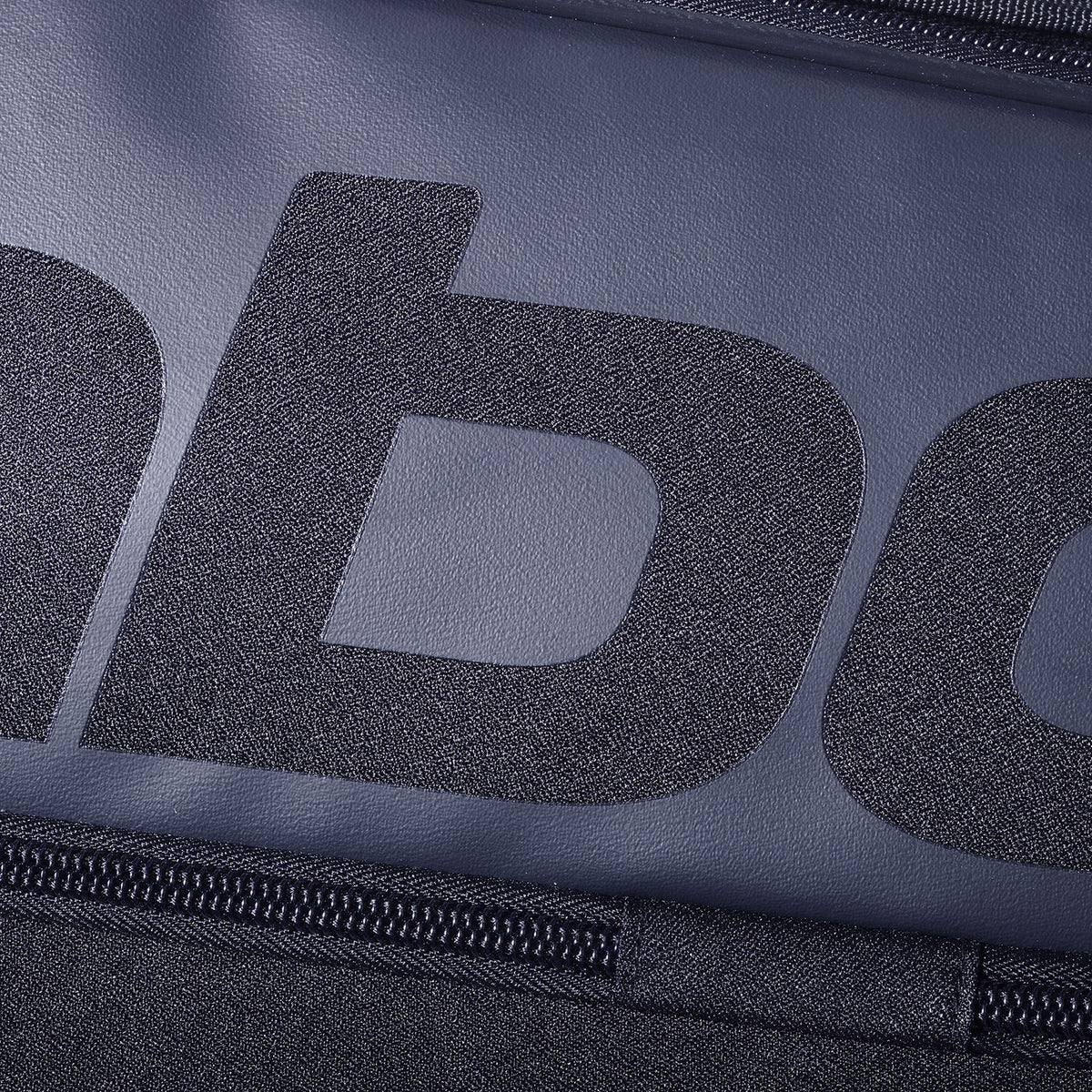 Close-up van het grijze Babolat logo en de rits op de zwarte rackettas