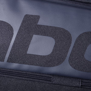 Close-up van het grijze Babolat logo en de rits op de zwarte rackettas