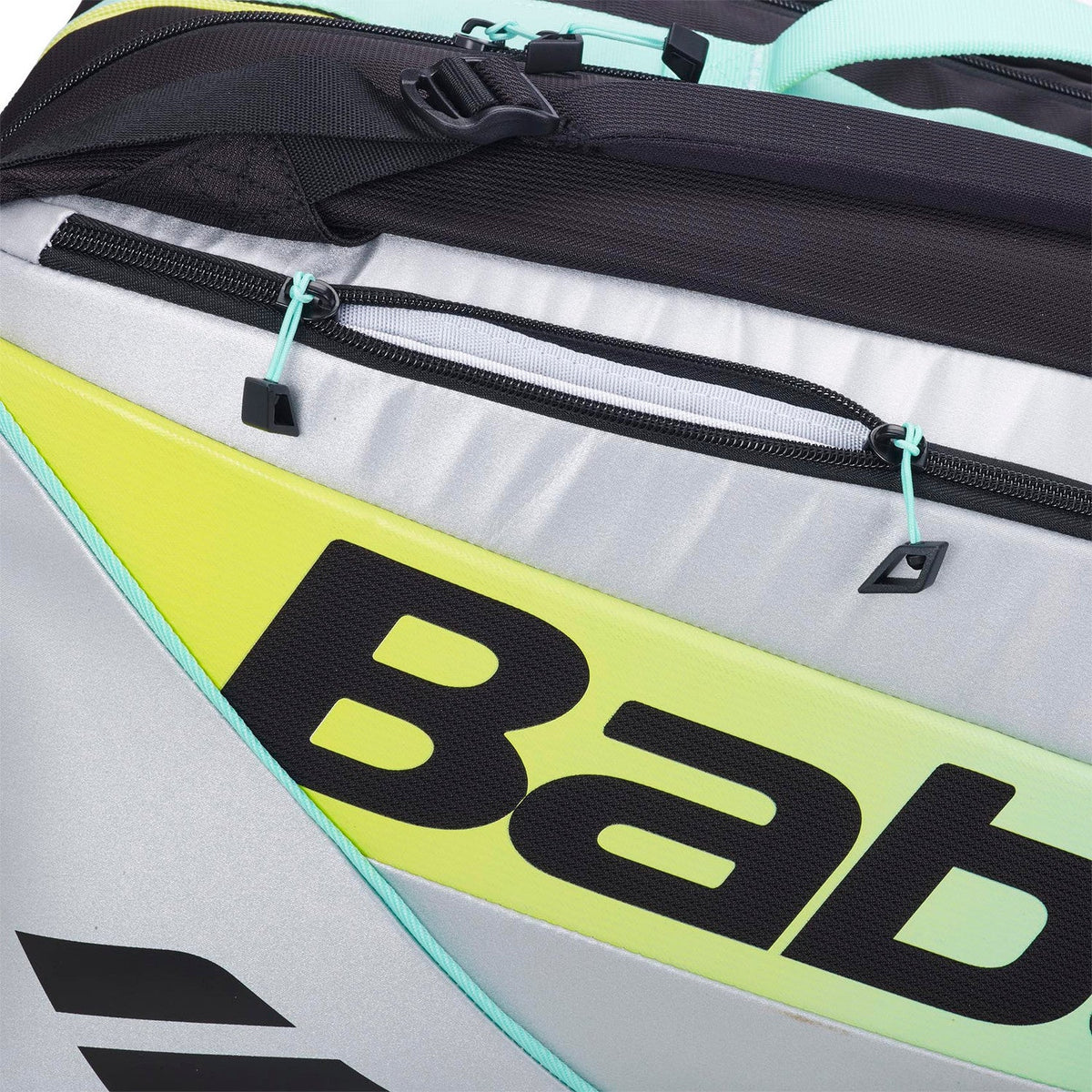 Detail van de gele Babolat opdruk op het witte paneel met mintgroene rits