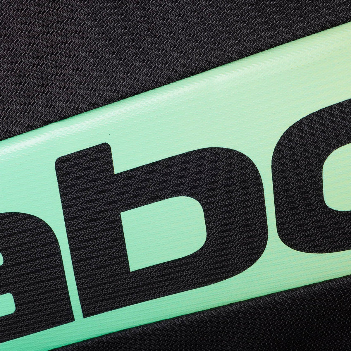 Close-up van het zwarte Babolat logo op de mintgroene band van de tas