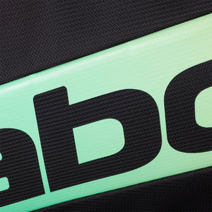Close-up van het zwarte Babolat logo op de mintgroene band van de tas