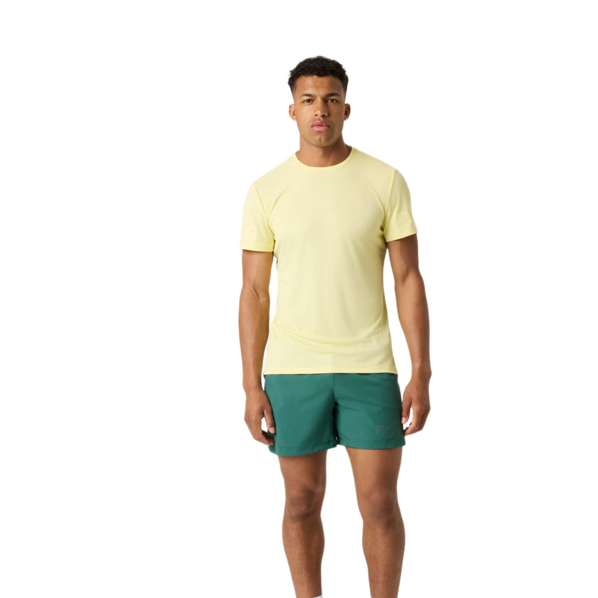 Model draagt de groene Bjorn Borg 6 inch short met geel T-shirt