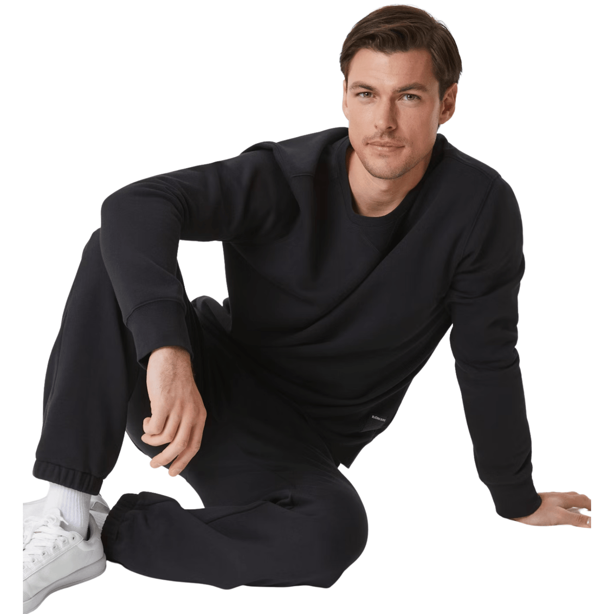 Model zit op de grond in het zwarte Bjorn Borg Centre Crew sweatshirt met zwarte broek