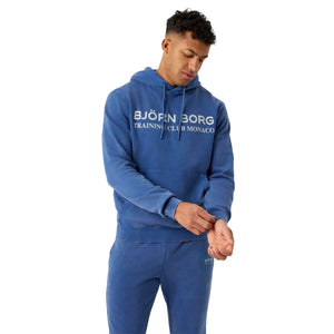 Model draagt de blauwe Bjorn Borg Classic Print Hoodie met bijpassende blauwe joggingbroek