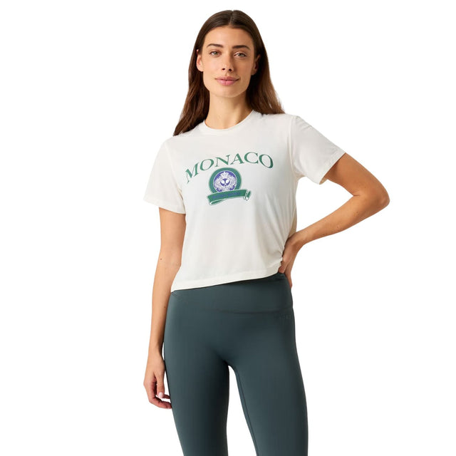 Damesmodel draagt het witte Bjorn Borg Cropped T-Shirt met Monaco print en donkere legging