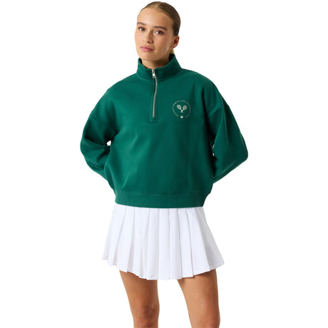 Model draagt de groene Bjorn Borg sweater met halve rits en witte plisserok