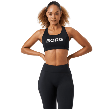 Damesmodel draagt de zwarte Bjorn Borg Mid Support Sports Bra met zwarte legging