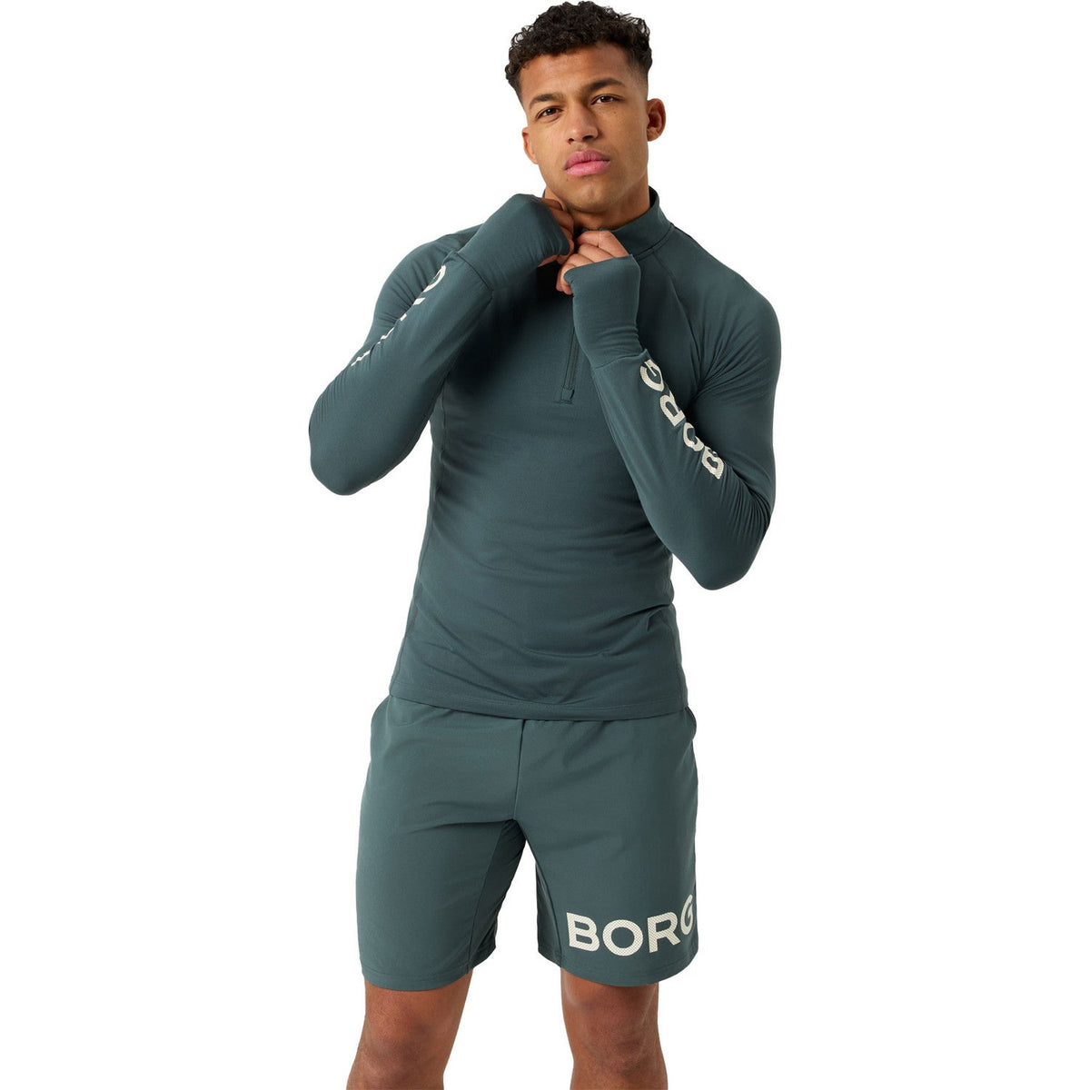 Model draagt de donkergroene Bjorn Borg trui met halve rits en short