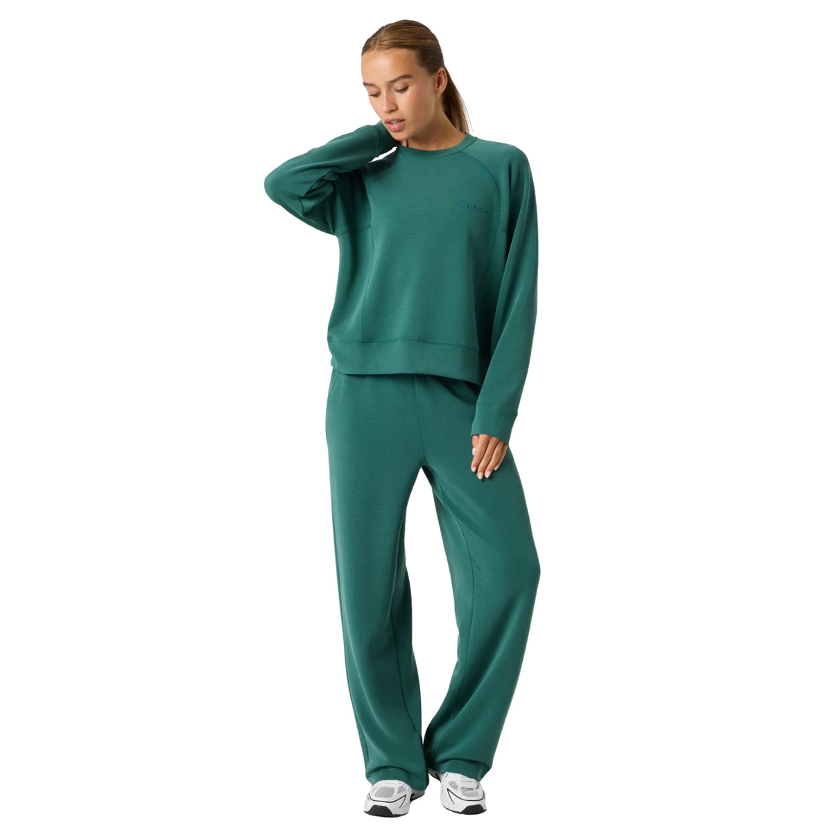 Model draagt de Bjorn Borg Studio Soft set in groen met sweater en wijde broek