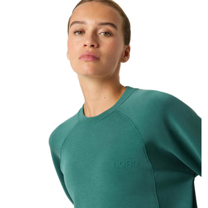 Close-up van de ronde hals en het logo op de groene Bjorn Borg Studio Soft sweater