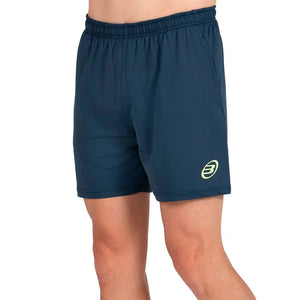 Model draagt de donkerblauwe Bullpadel Short Lijar met geel Bullpadel-logo op de pijp