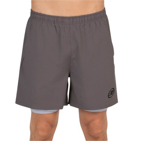 Vooraanzicht van de donkergrijze Bullpadel Short Manzan met wit logo op de linkerpijp