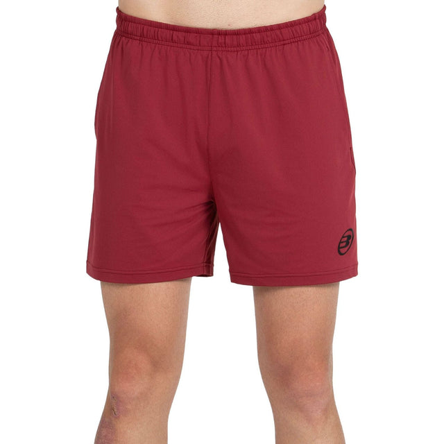 Vooraanzicht van de bordeauxrode Bullpadel Short Monfort met zwart logo op de pijp