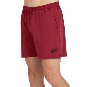 Schuin aanzicht van de bordeauxrode Bullpadel Short Monfort met steekzak en logo