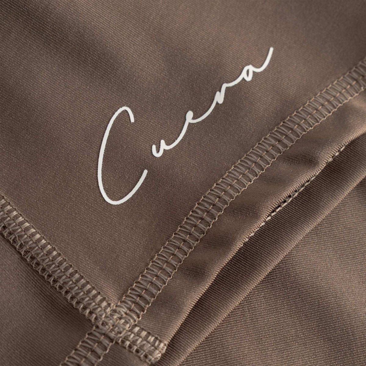 Detail van het witte Cuera-logo en de stiksels op de Biker Tights Hidden Seem Walnut