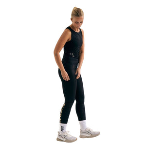 Model draagt de zwarte Cuera Active Logo Tights met zwarte tanktop en witte sneakers