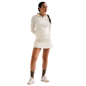 Model draagt de witte Cuera Oncourt Skirt 2-In-1 met lichte longsleeve op de baan