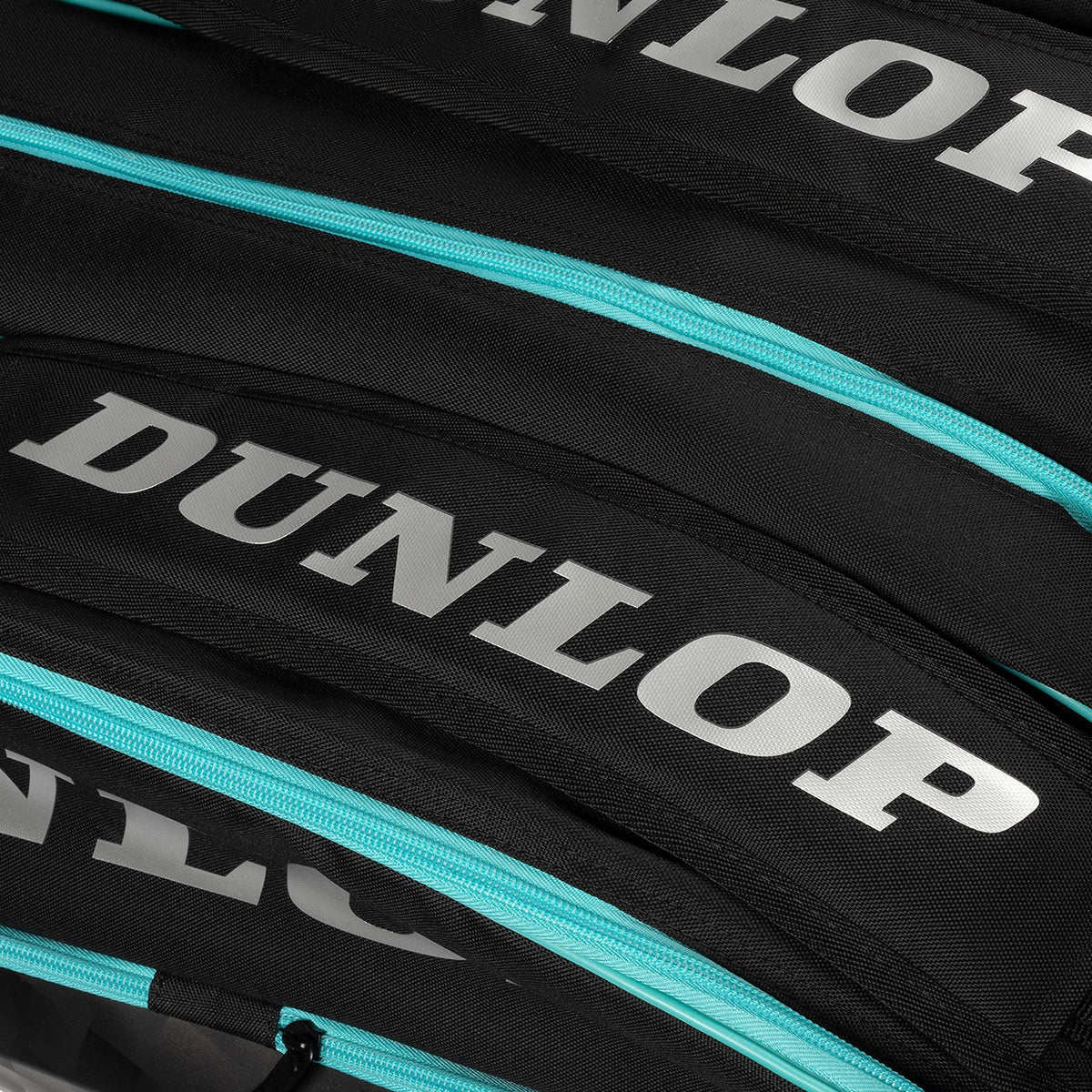 Close-up van het zilvergrijze Dunlop-logo en de turquoise ritsen op de zwarte Elite padeltas