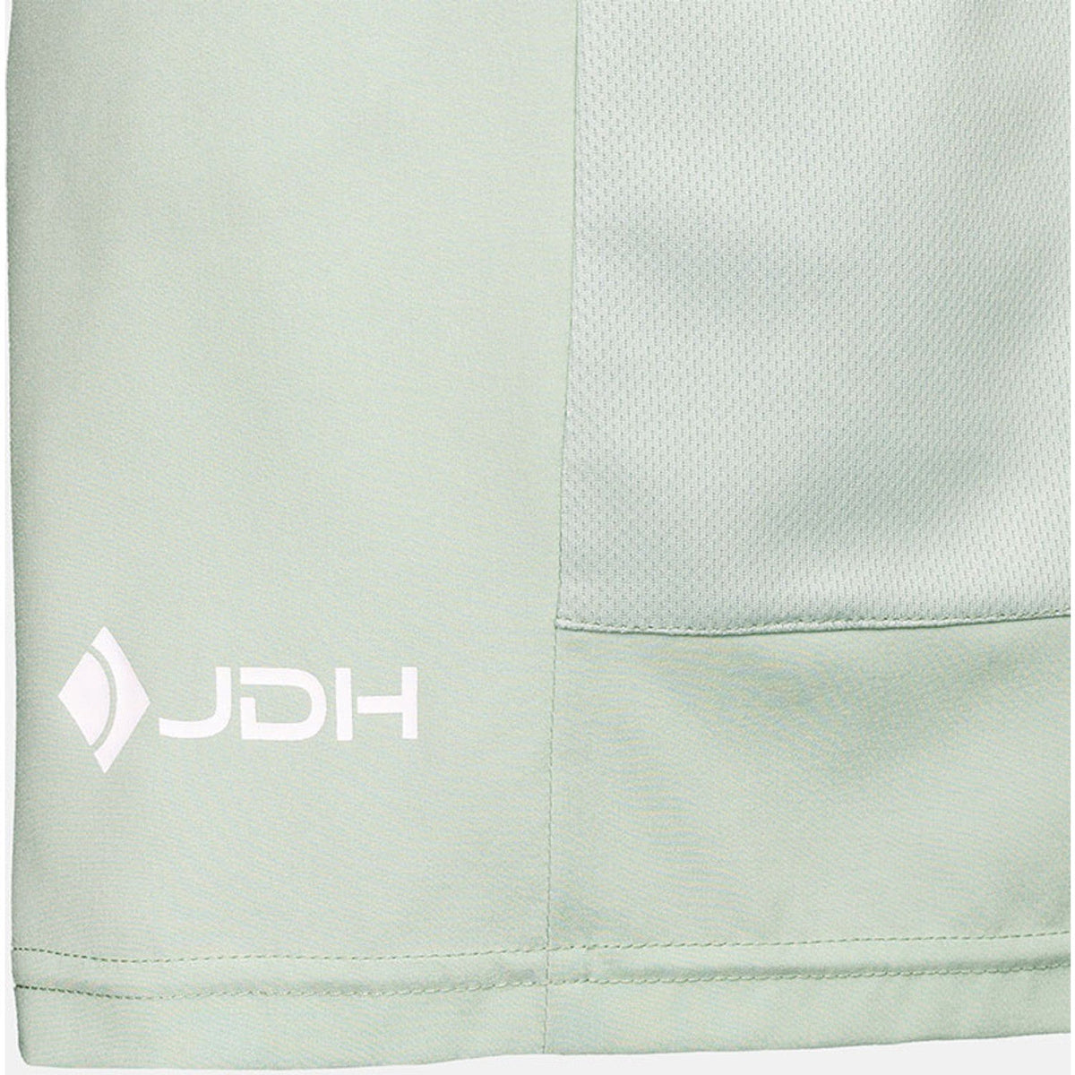 Detail van het witte JDH-logo op het mintgroene paneel van de Performance Short
