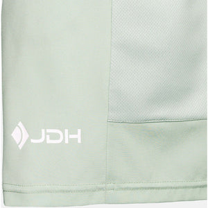 Detail van het witte JDH-logo op het mintgroene paneel van de Performance Short