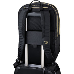 Wilson Defy V1 rugzak over de uitschuifbare handgreep van een koffer geschoven